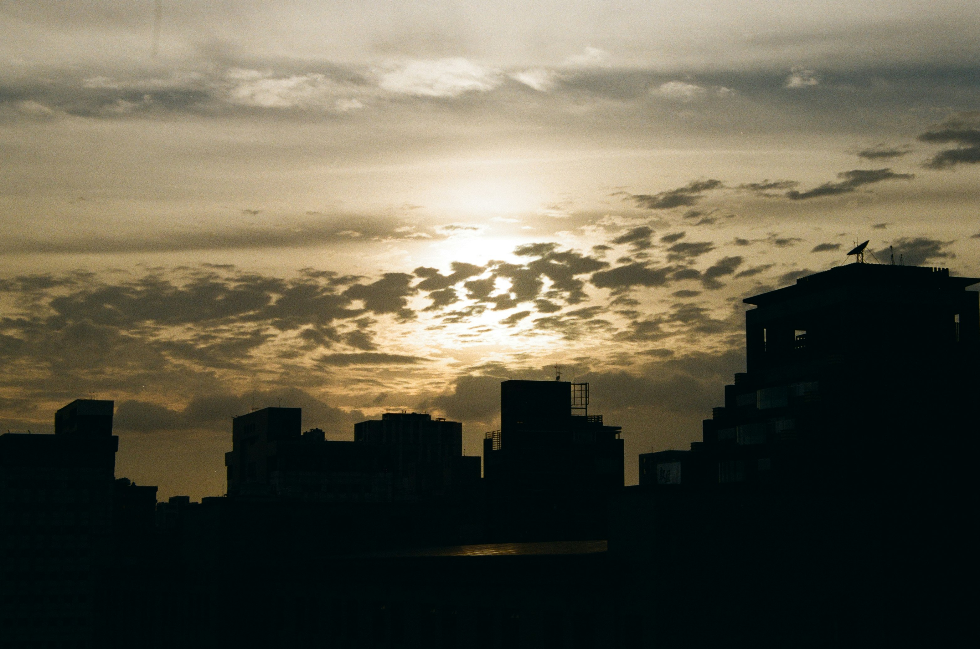 silhouette of buildings under cloudy sky during sunset